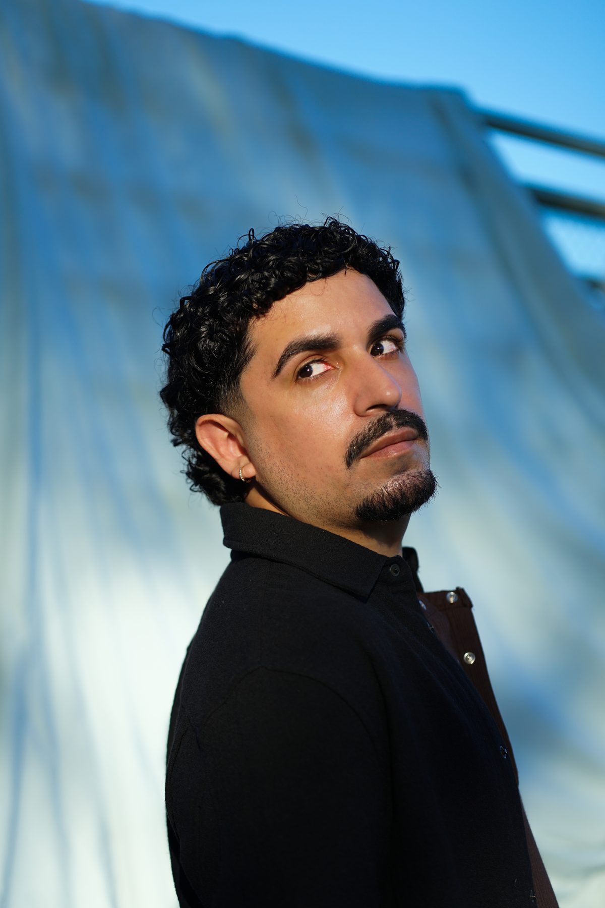Portrait of Daniel looking over his shoulder against a draped backdrop