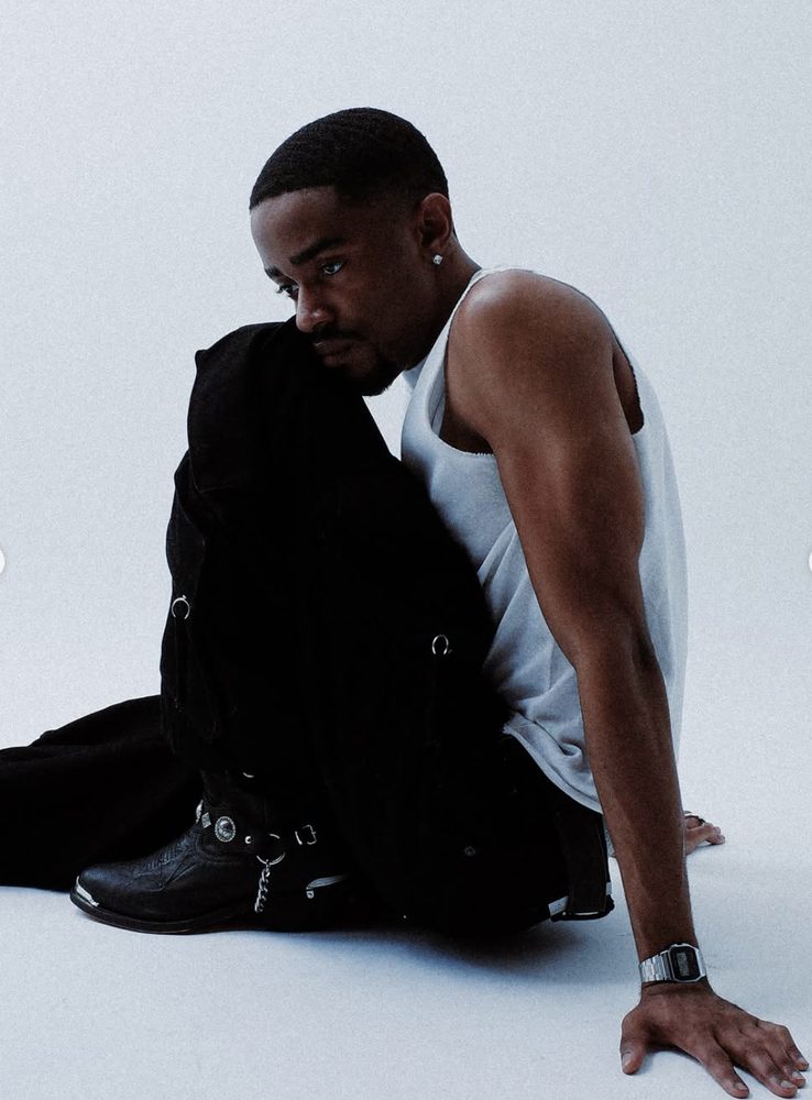 Nocturnus mood image — man in a white vest and dark jacket seated on a studio floor