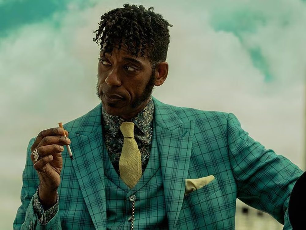 Nocturnus mood image — man in a teal checked three-piece suit holding a cigarette