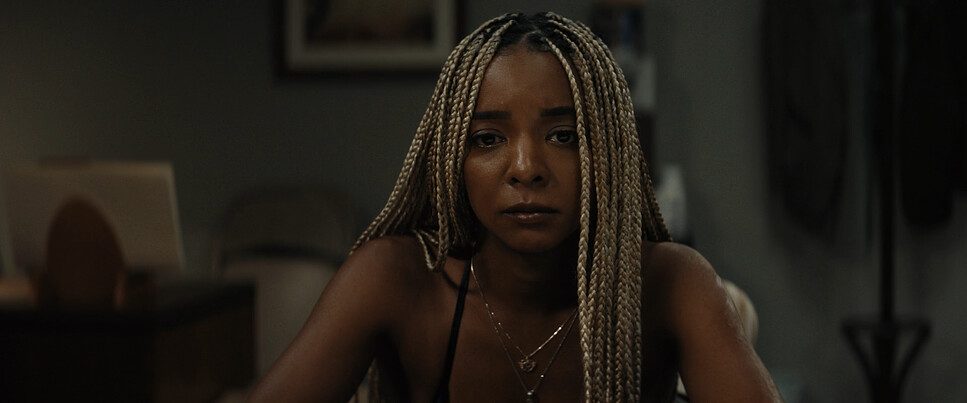 Sagrados mood image — woman with long braids seated in a dim room